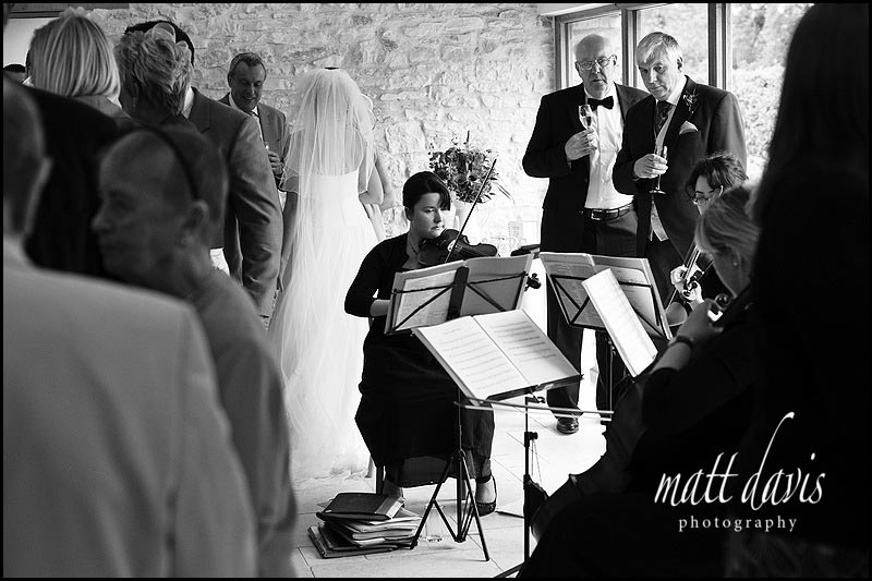 Wedding drinks reception indoors at Kingscote Barn with quartet playing